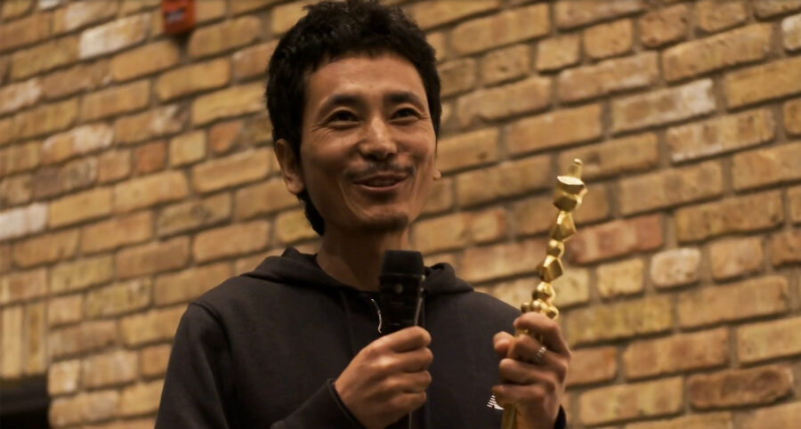 artist tenzin gyurmey holding the rubin art prize and speaking into a microphone