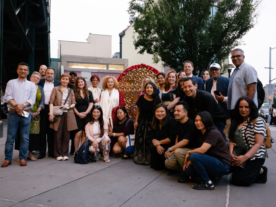 twenty six adults standing and smiling in front of IMAGINE's sculpture, About a Living Culture