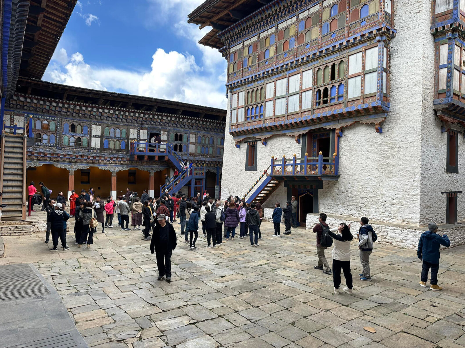 internal view of the Wangduechhoeling Palace with people walking through on a cobbled ground