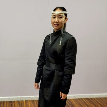 Galina Badmaeva smiling, wearing black traditional dress and a white headpiece