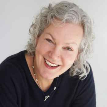 A smiling woman with short wavy gray hair wearing a black shirt