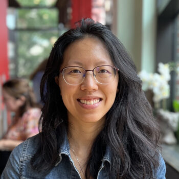 smiling adult woman with black hair wearing glasses