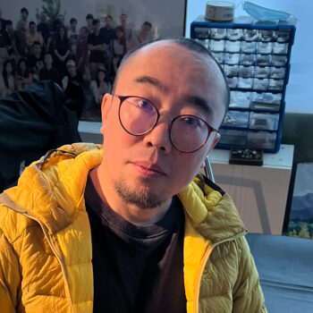 an adult man wearing glasses and a yellow jacket