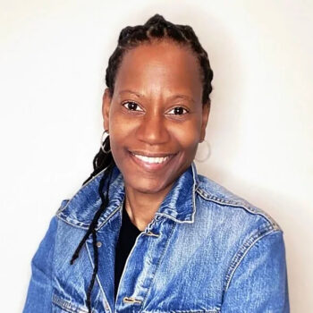 A smiling woman with black hair wearing a denim jacket