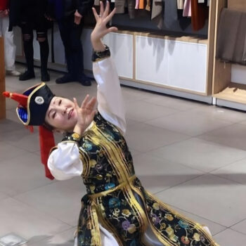 Sodnom Damdin wearing a traditional dress, dancing with hands in the air