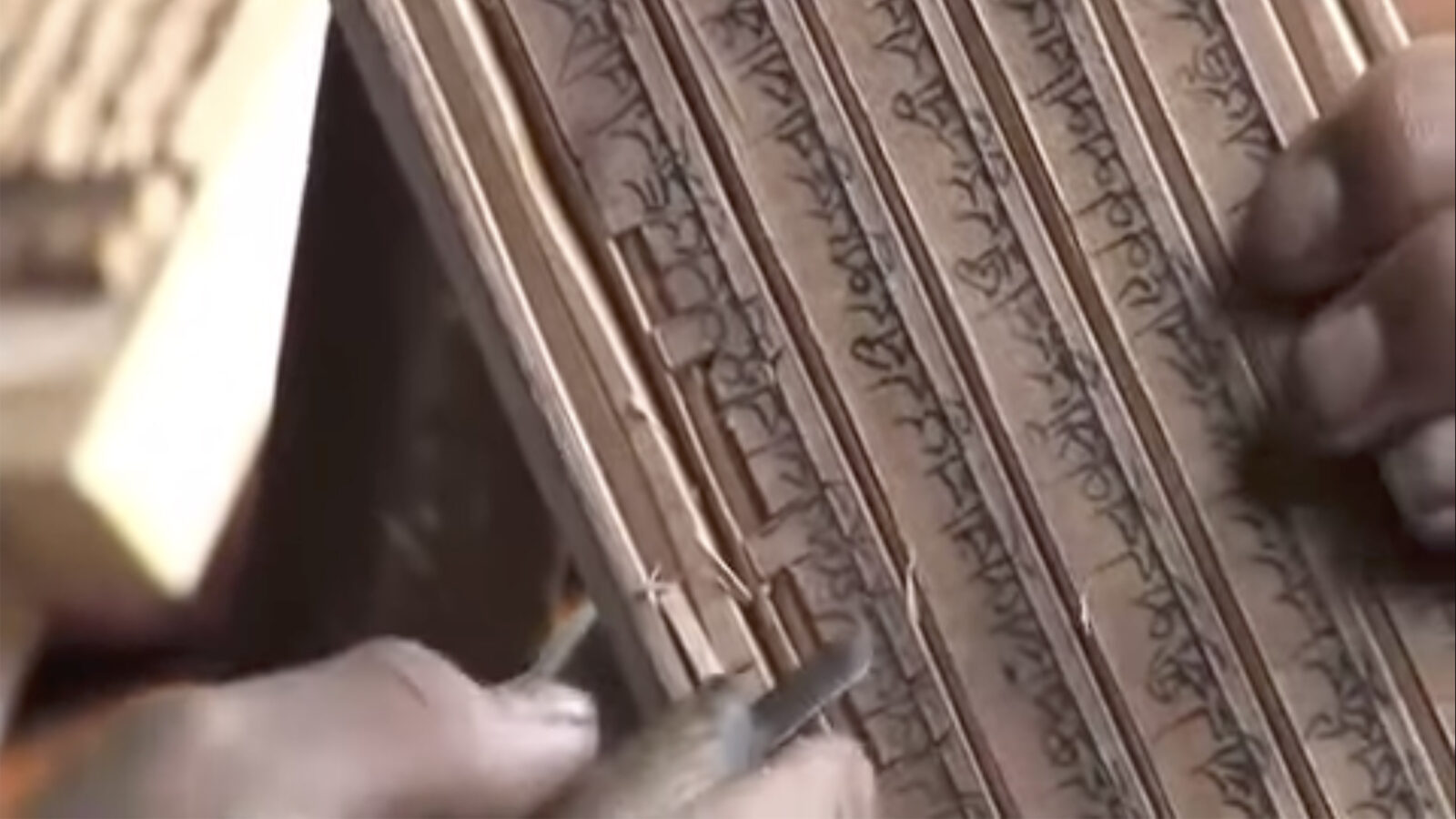 close up of hands holding a carving tool and a woodblock