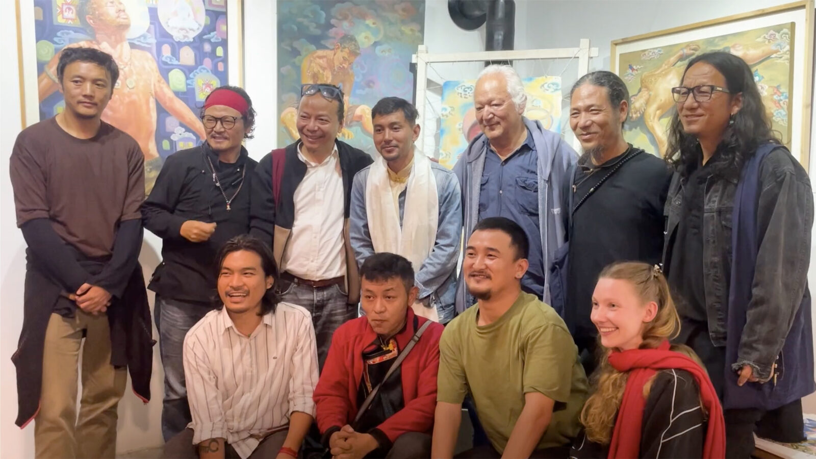 two rows of people smile and look to the side, with the front row kneeling while the back row stands