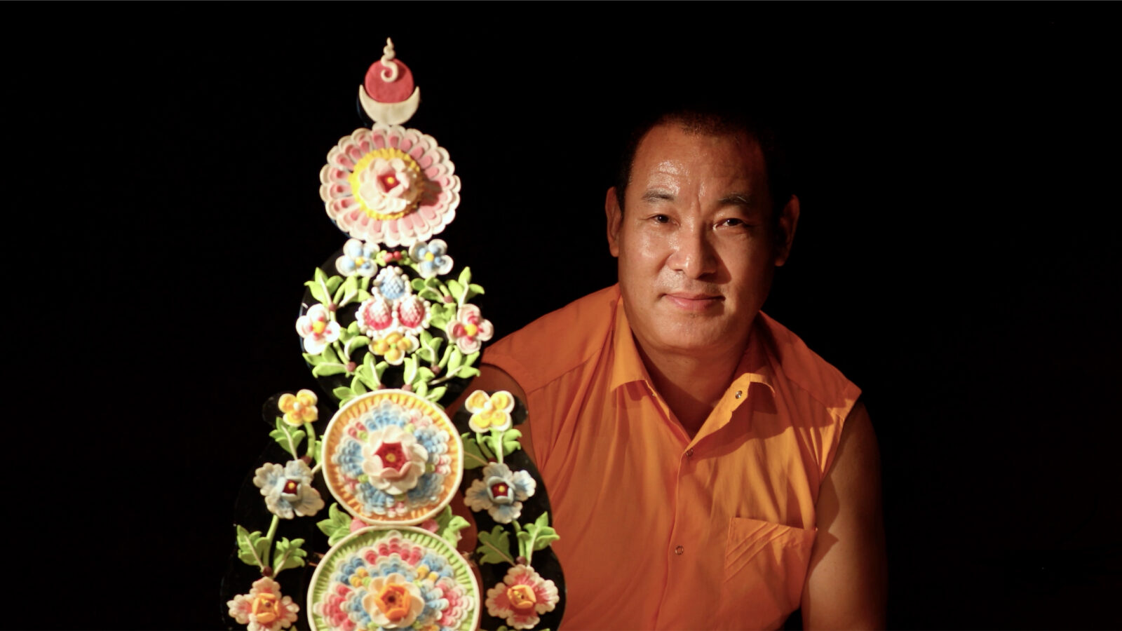 A man behind a torma against a black background