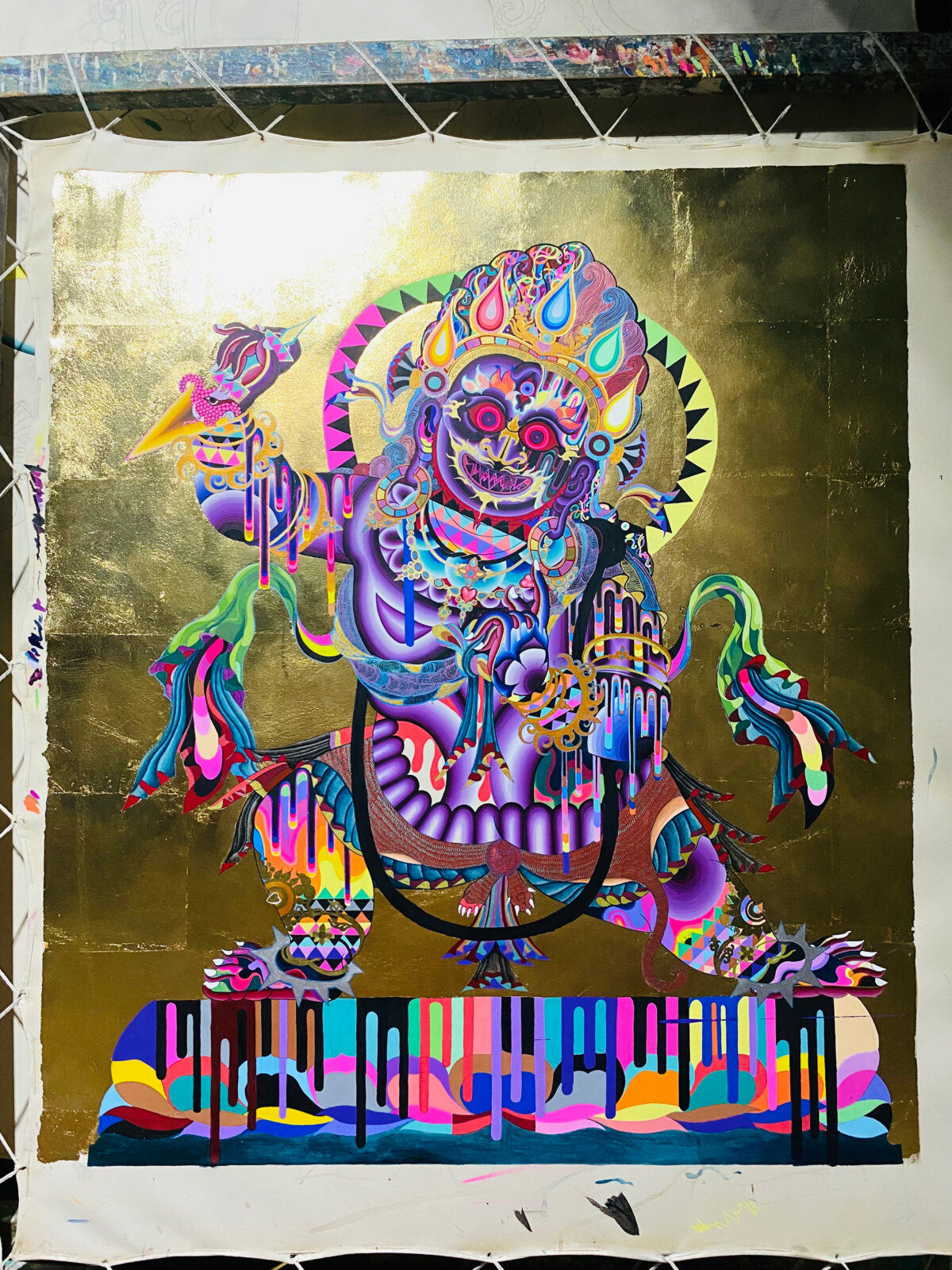 A colorful painting of a deity on a gold leaf background