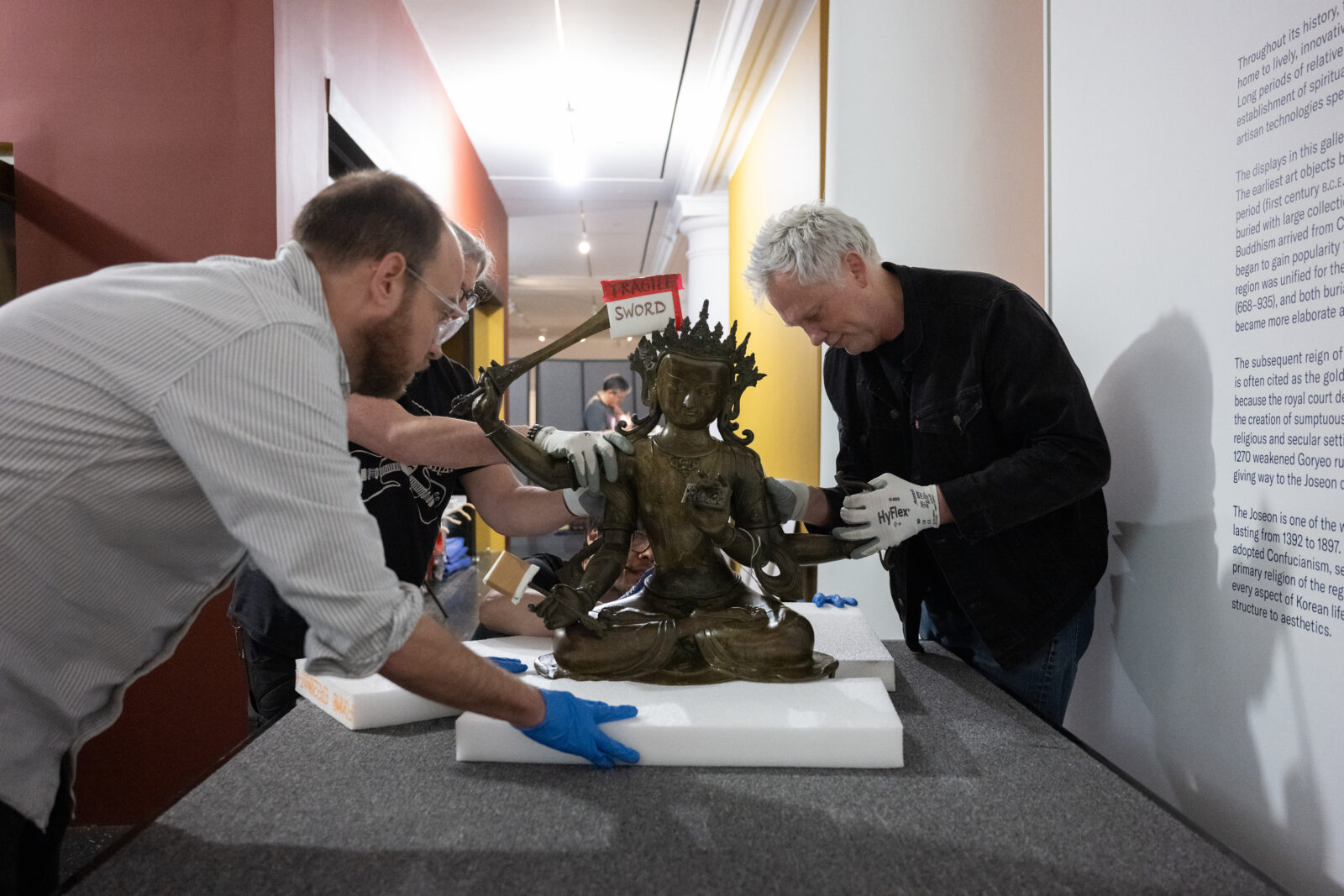 art handlers carefully move a sculpture