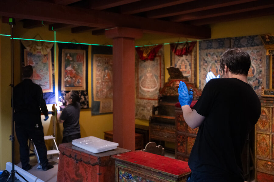 an art handler lines up a thangka on the wall of the Rubin Museum Tibetan Buddhist Shrine Room installation