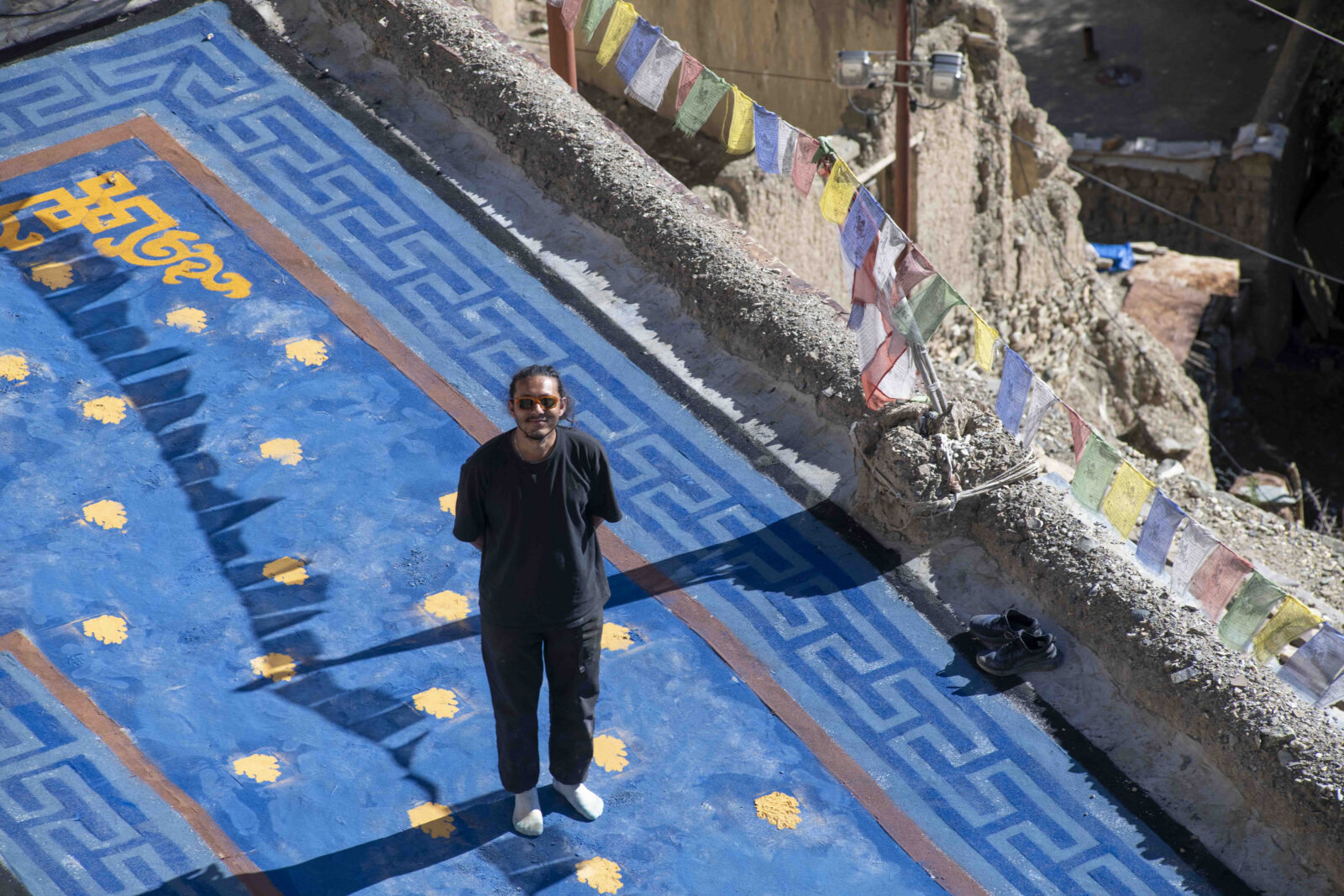An overhead view of a man standing on a blue rooftop, smiling and looking up
