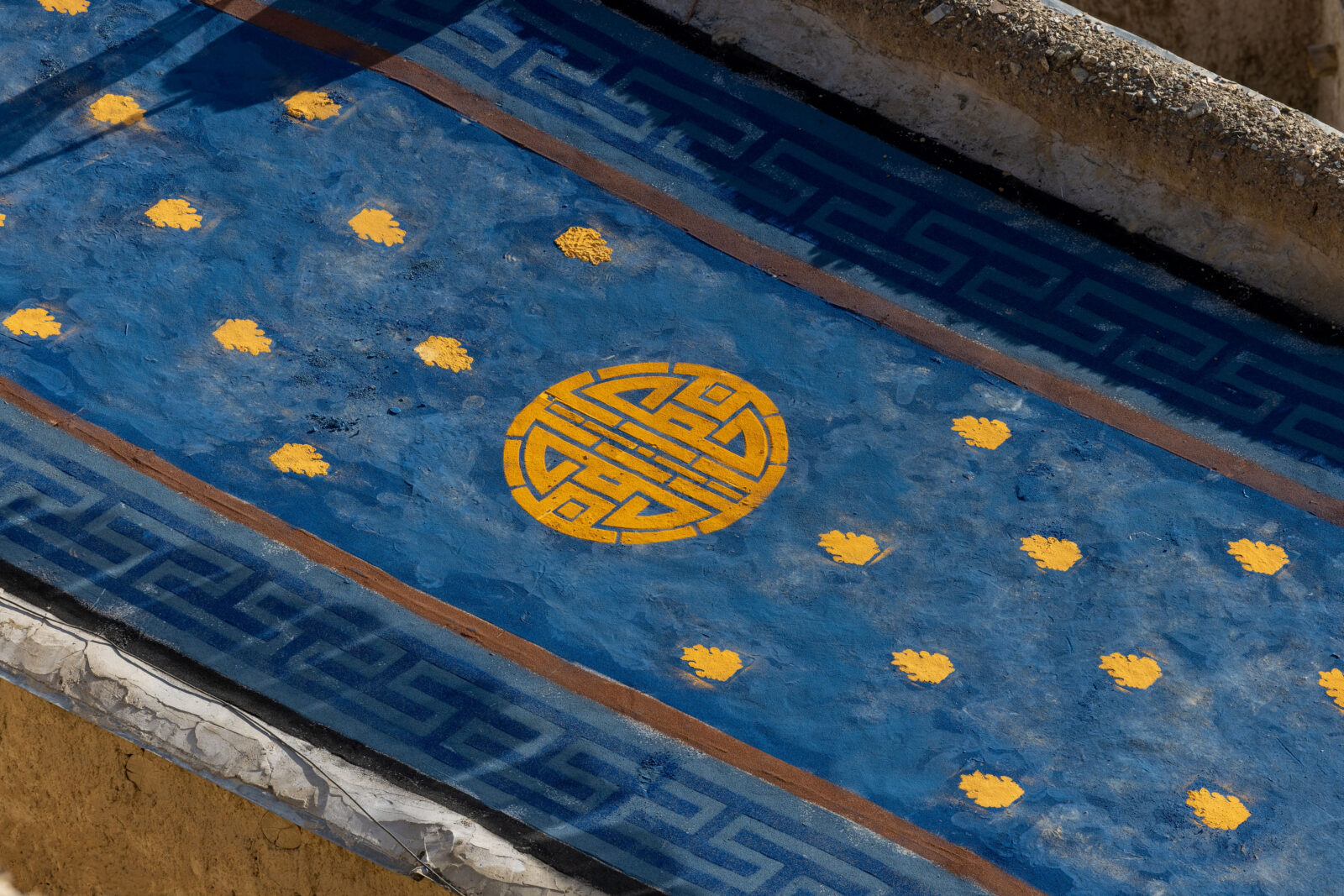 Overhead view of a rectangular blue rooftop with a gold circular design in the center and gold geometric shapes to the left and right