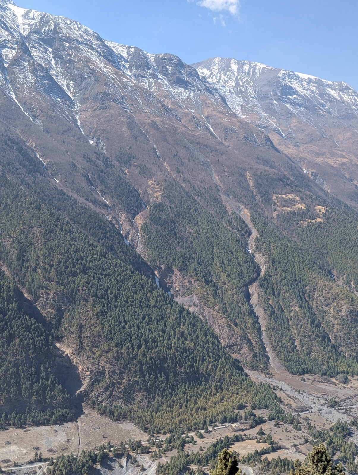 closeup of large mountain slope with snow capped mountain range in background
