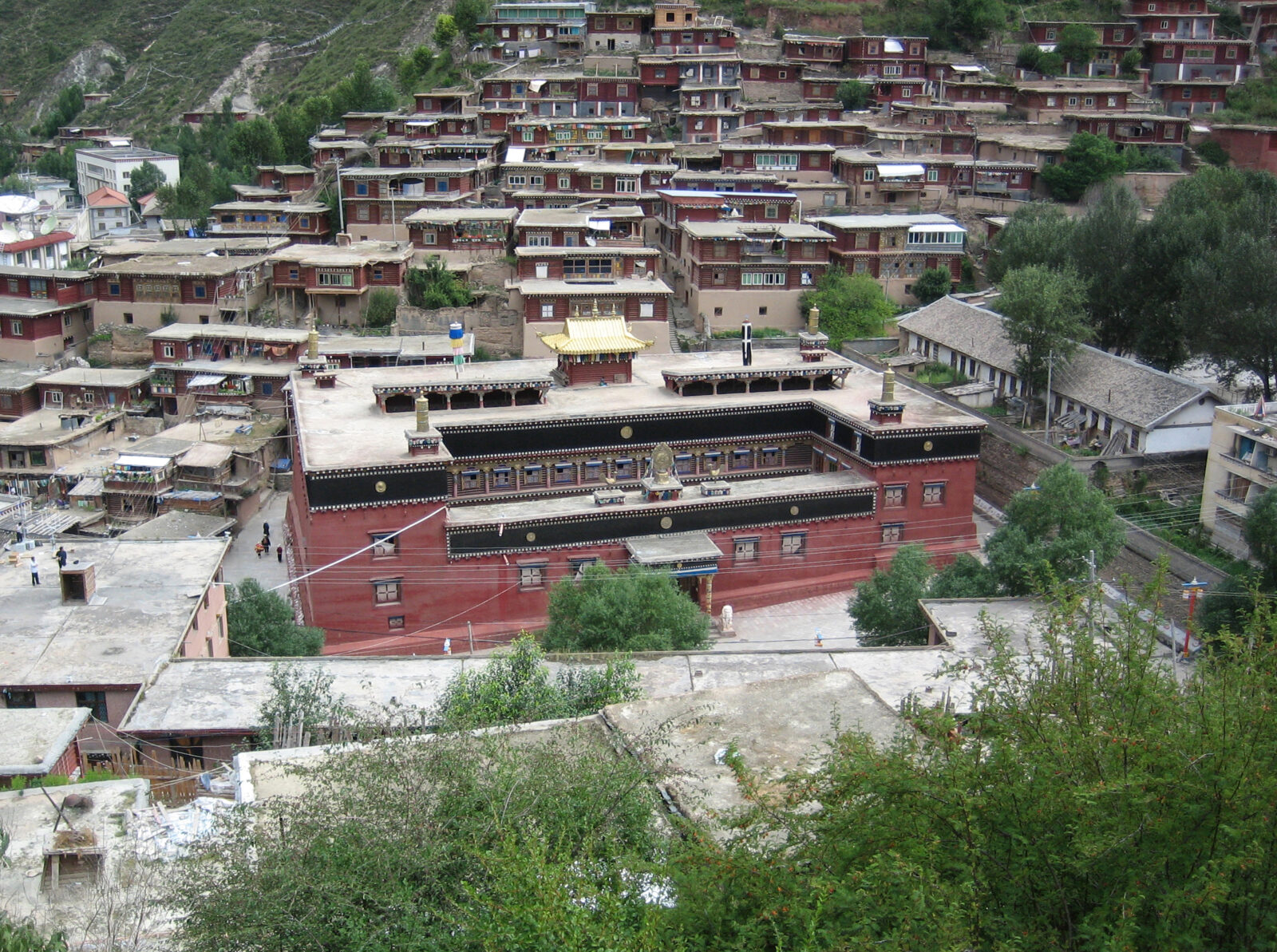 Aerial view of a red building with black trimming and a white roof. The building is surrounded by other smaller buildings.