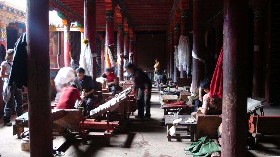 people in a room with tall columns and printing equipment