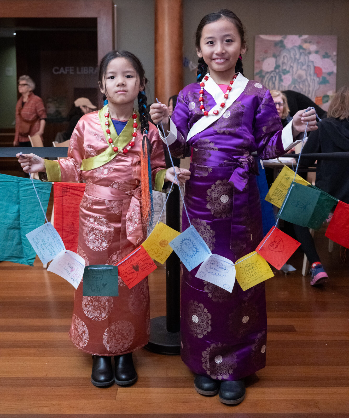 two children holding colorful strings of prayer flags