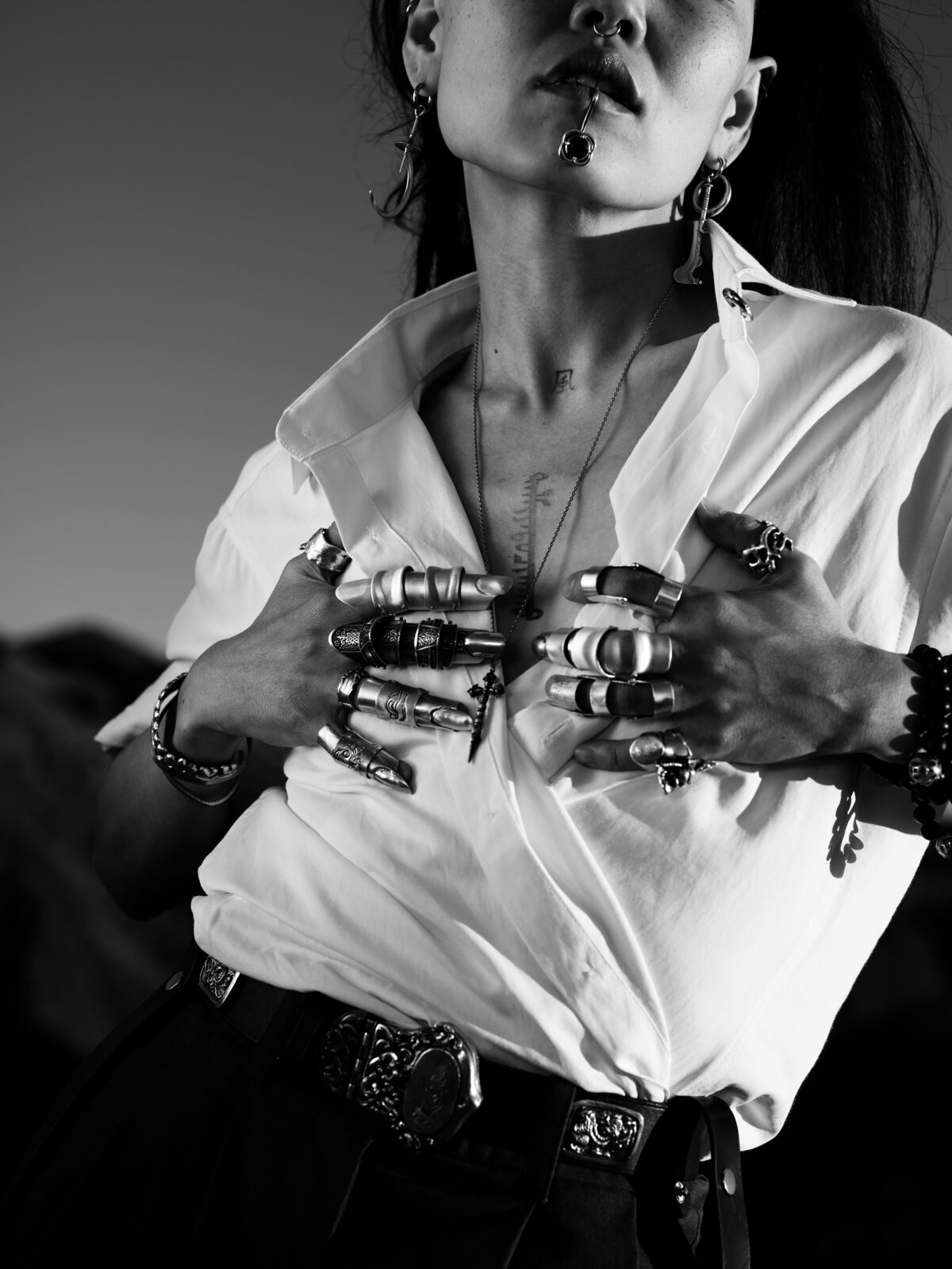 Black and white photo of an adult holding hands up to their chest, with rings in every finger