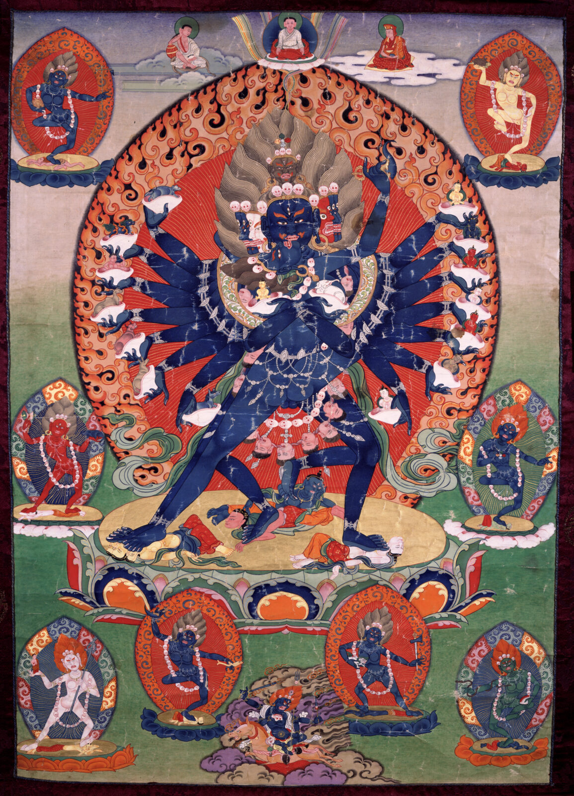 Painting of multi-limbed blue figure standing on lotus blossom, surrounded by three smaller seated figures above and smaller standing figures on both sides and below.