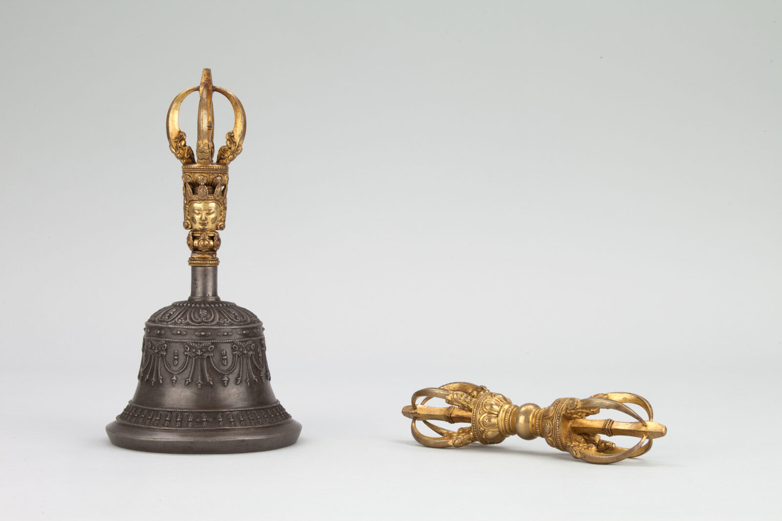 Bell on right side with gold handle. Gold vajra, five-pronged ritual object, on right side.