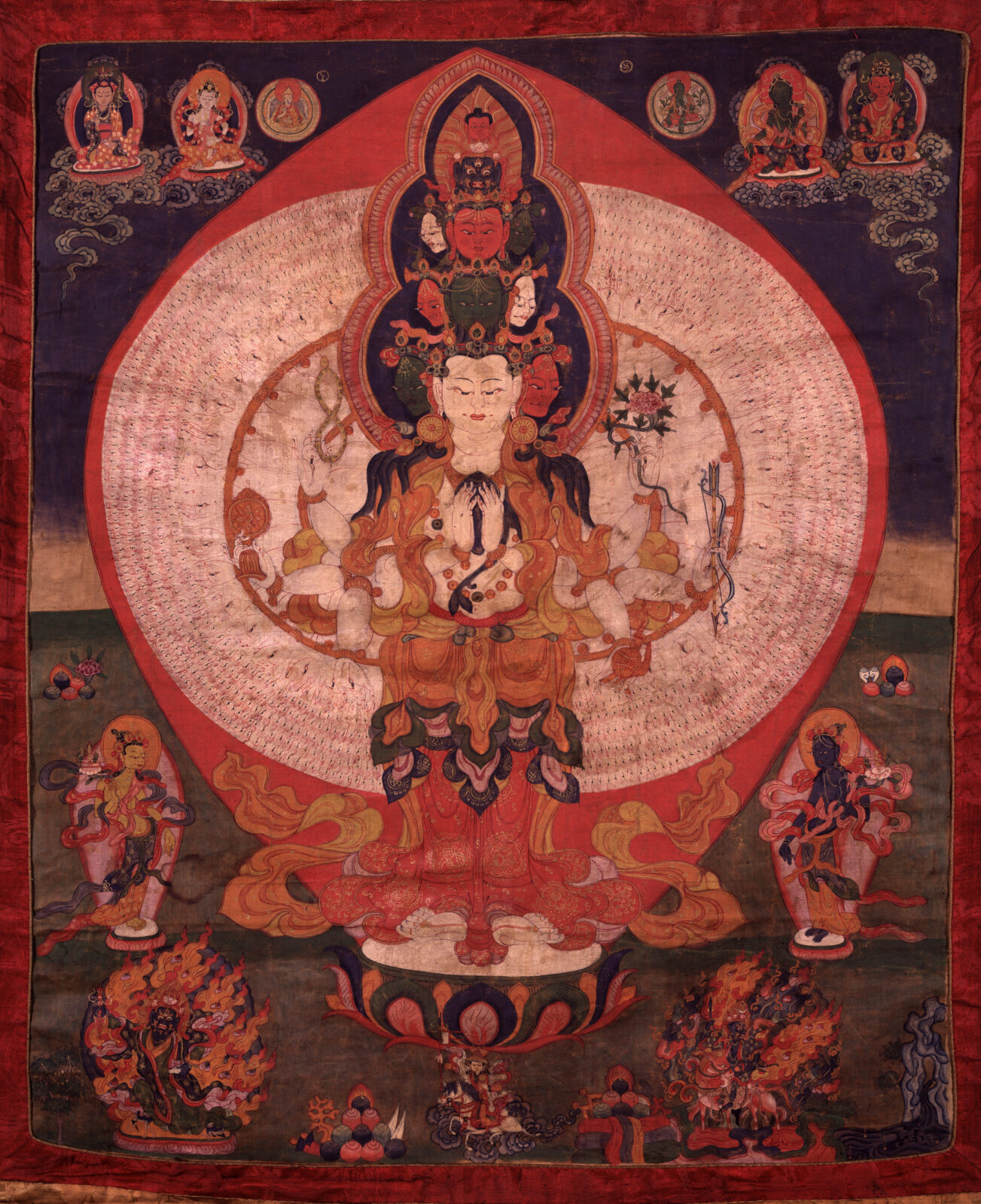 Painting of large figure with many arms and heads standing on a lotus blossom, surrounded by smaller figures with flowing robes.