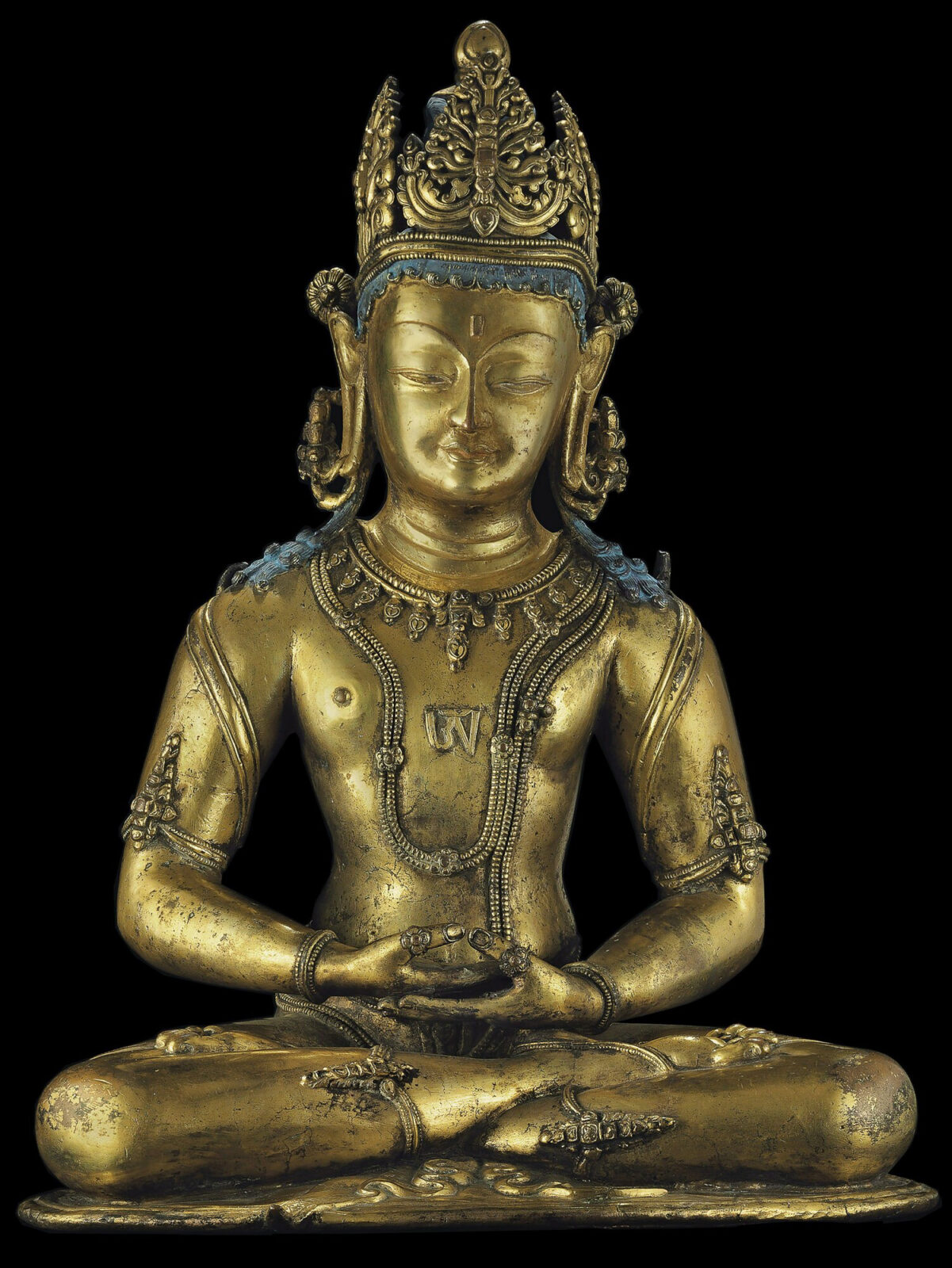 Golden statue of figure with crown seated on lotus blossom.