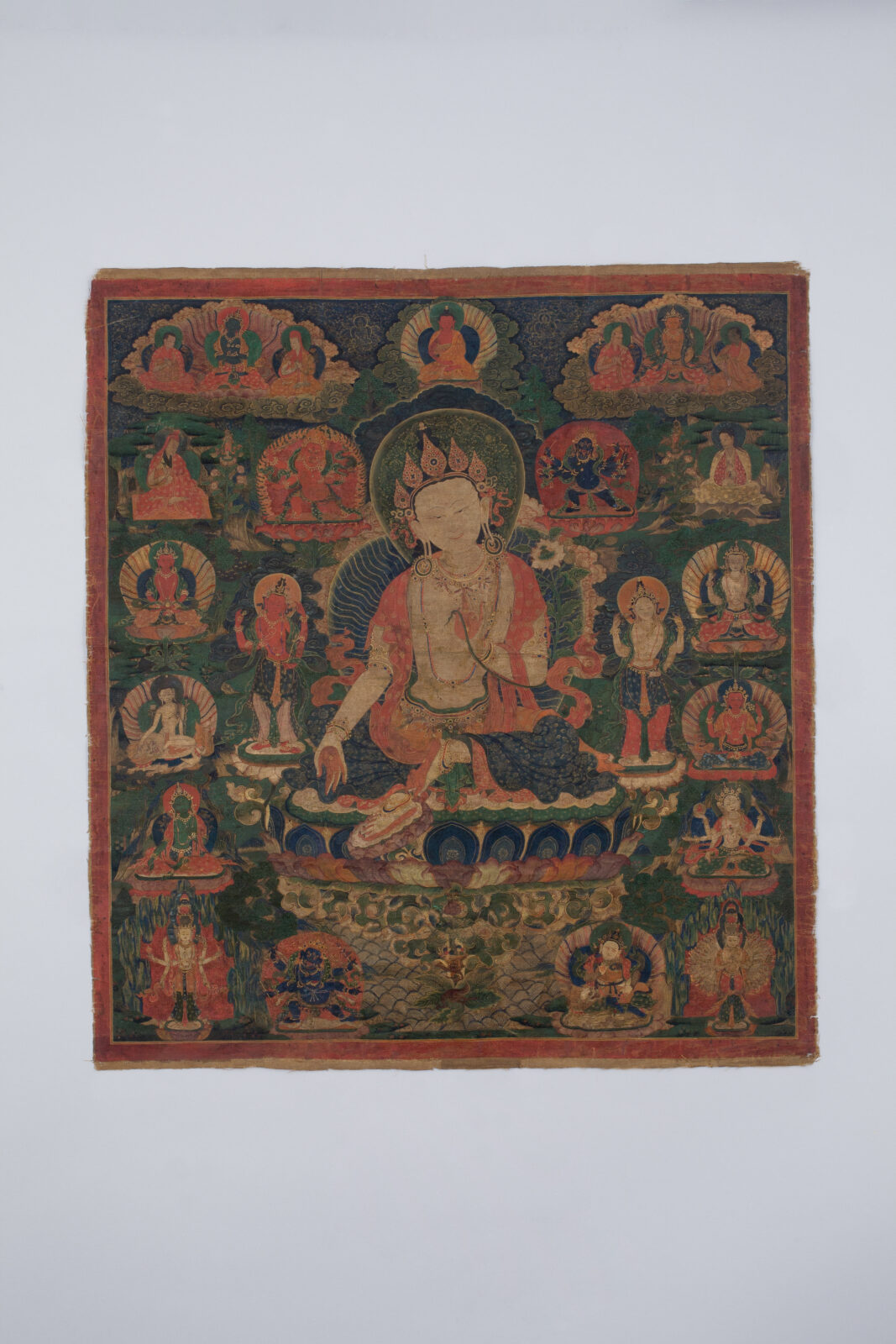 Painting of seated figure on lotus blossom surrounded by smaller figures.