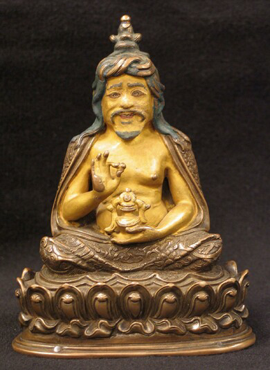 Small painted statue of figure seated cross-legged on lotus blossom.