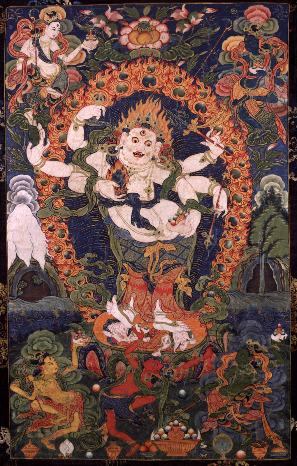 Painting of multi-armed figure standing on lotus blossom, surround by smaller figures in flowing robes.