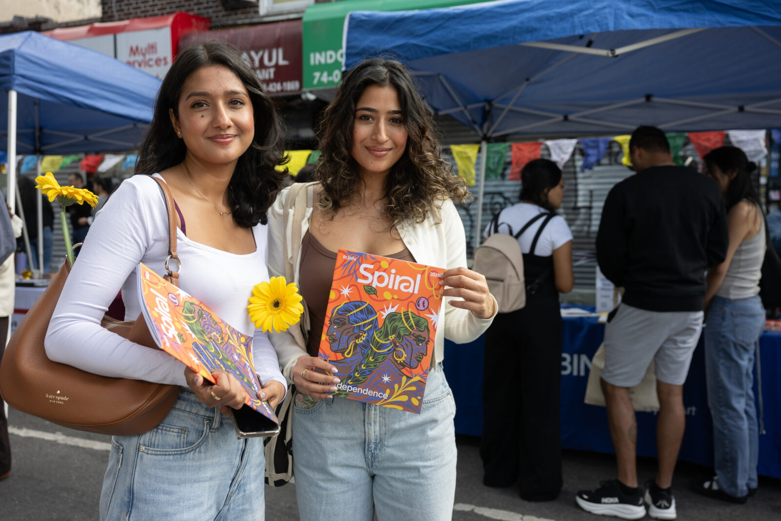 two adults smile while holding up a magazine with the titled "Spiral"