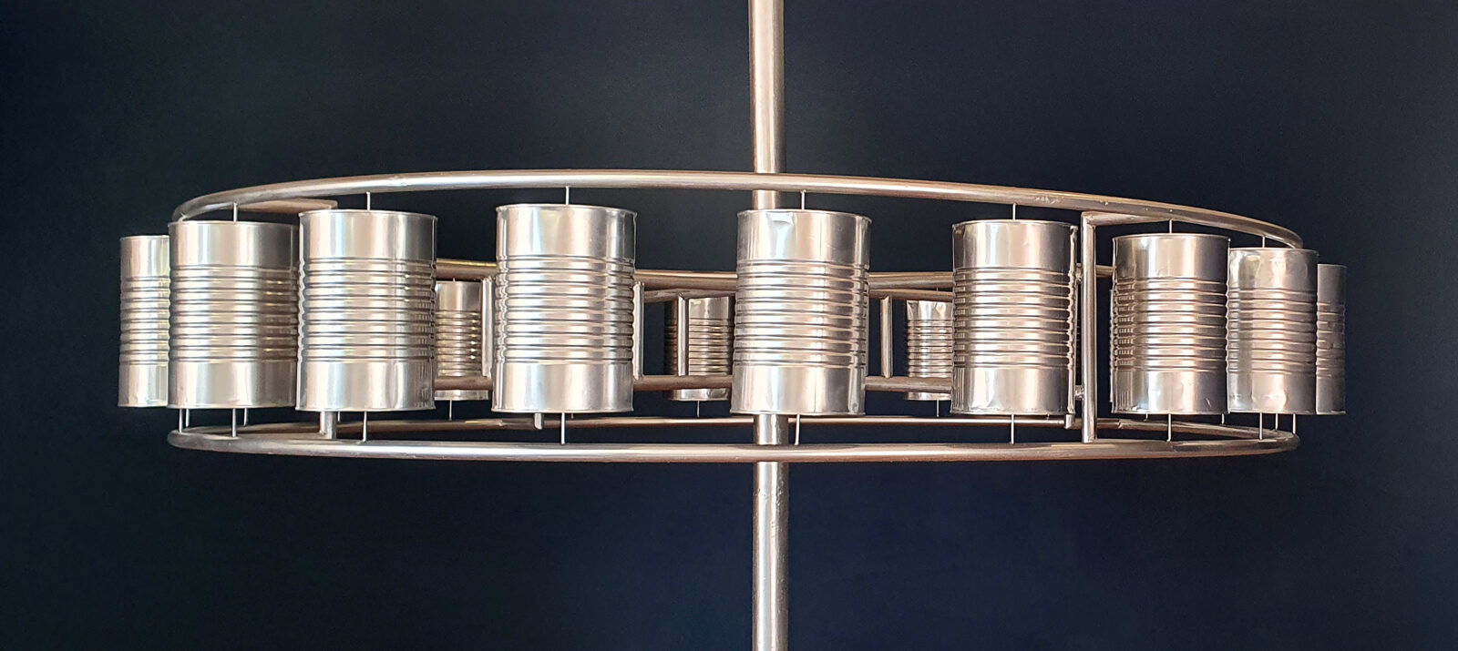 sculpture of tin cans welded to a circular metal form, mounted on a central metal pole