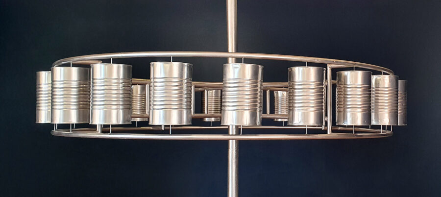 sculpture of tin cans welded to a circular metal form, mounted on a central metal pole