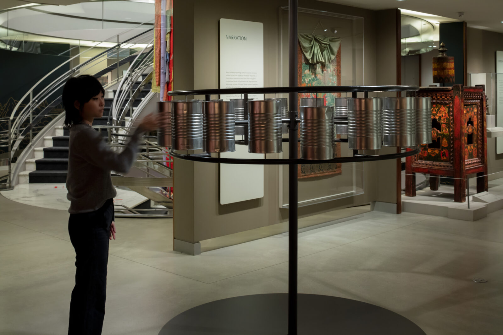an adult touches an interactive metal sculpture in a gallery