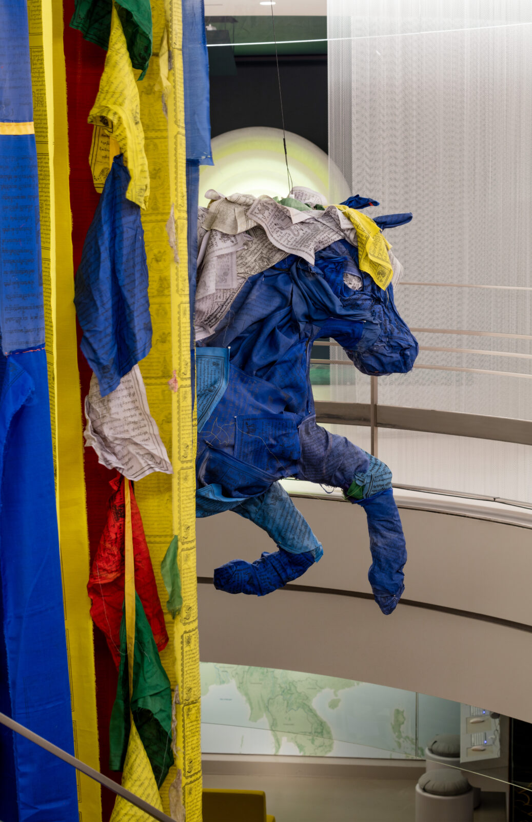 Prayer flags sculpted into a blue horse coming out of cascading prayer flags of yellow, white, red, and blue.