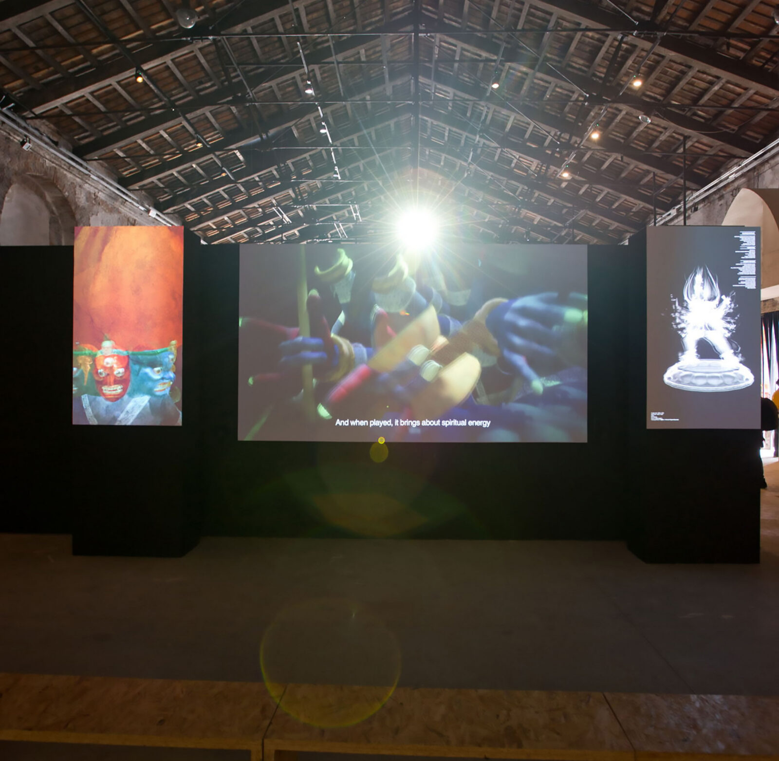 Three screens on a black wall displaying colorful videos