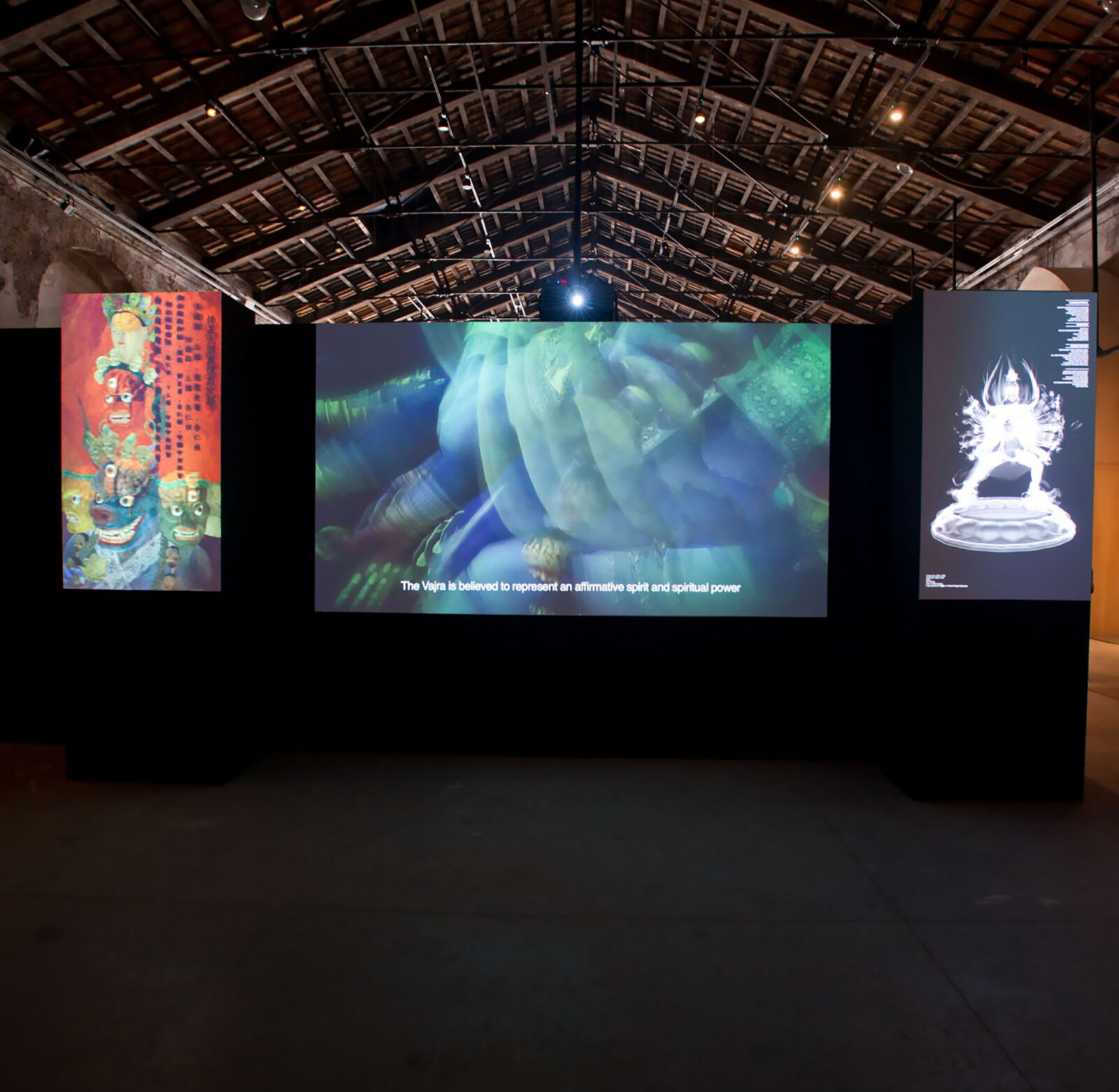 Three screens on a black wall displaying colorful videos